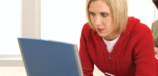 A woman in a red jumper looking at a laptop screen