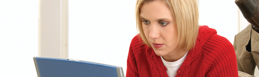 A woman in a red jumper looking at a laptop screen